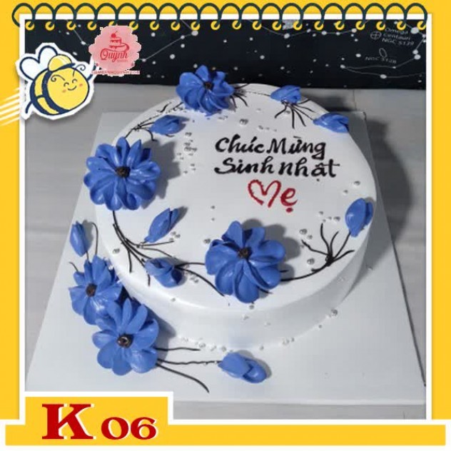 giới thiệu tổng quan Bánh kem tặng khách hàng K06 với các cành hoa uốn lượn màu xanh dương trên mặt bánh nền màu trắng